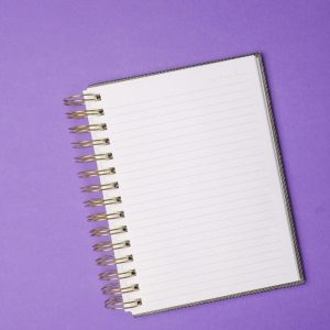 Top view of a spiral notebook on a vibrant purple and yellow background, perfect for design presentations.